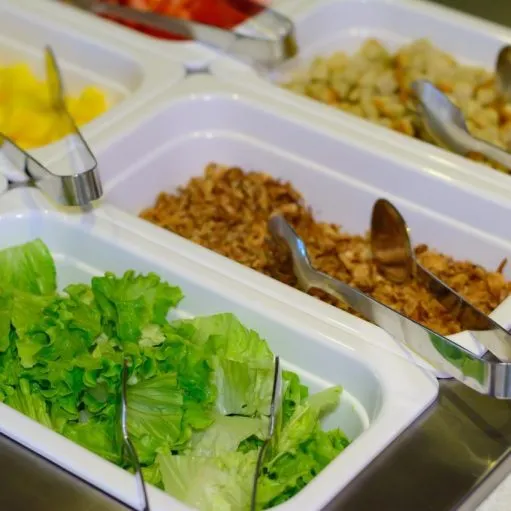 Bacs de salades et de crudités du buffet froid avec pinces de service
