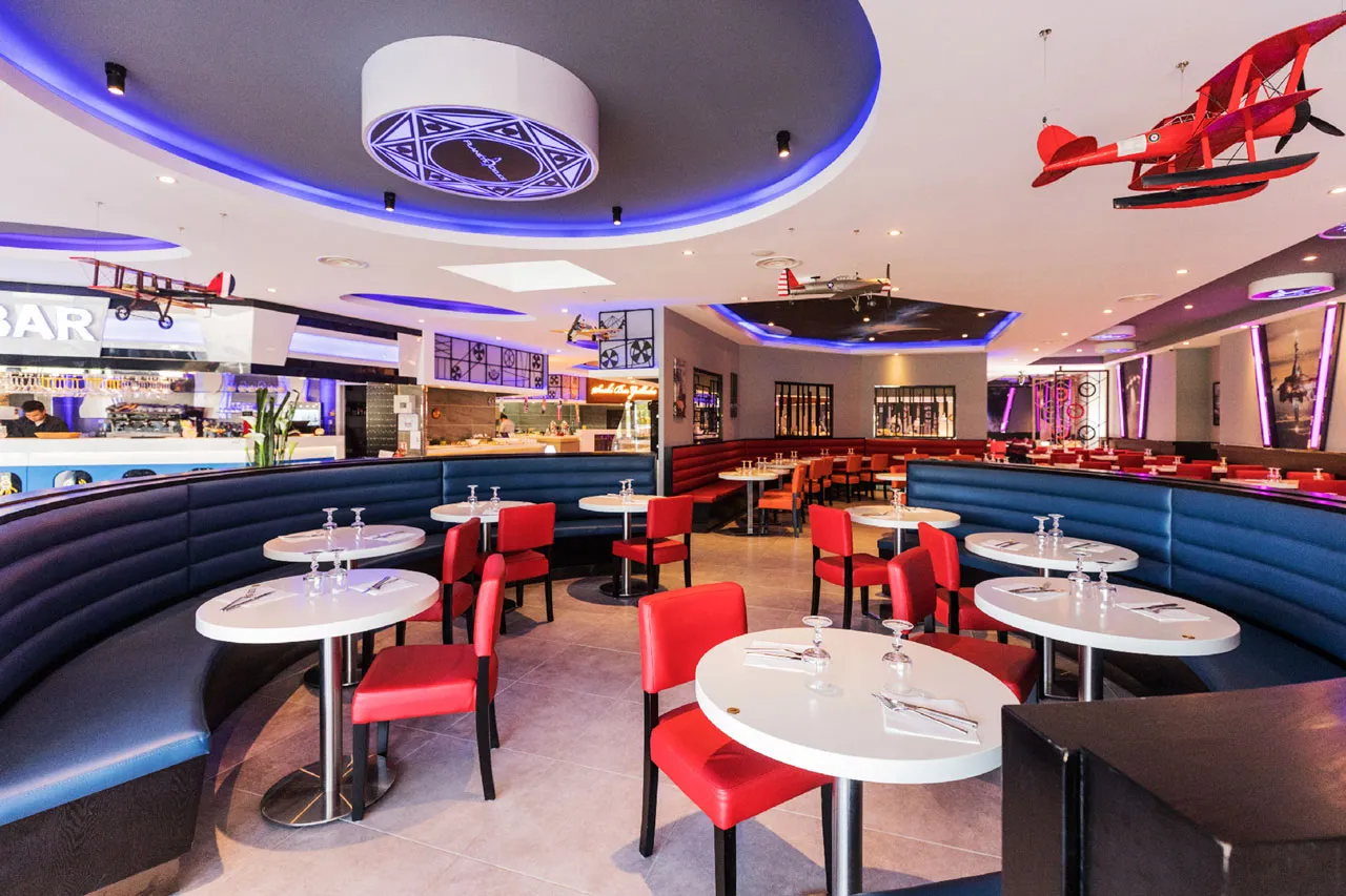 Banquettes arrondies, tables rondes et avions suspendus près du bar du restaurant