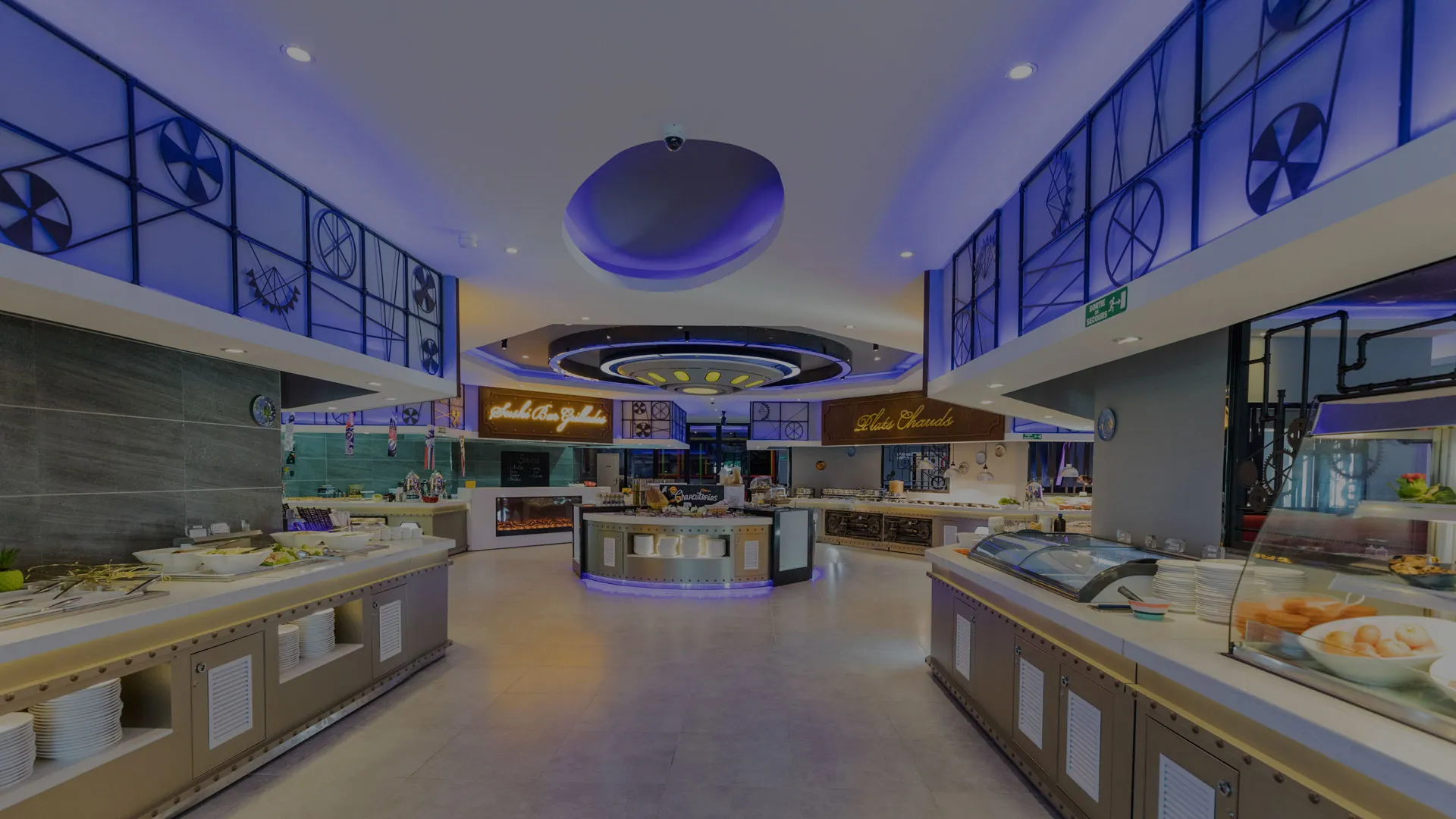 Salle de buffet de Planète Délice : îlot central éclairé et comptoirs sous une voûte violette